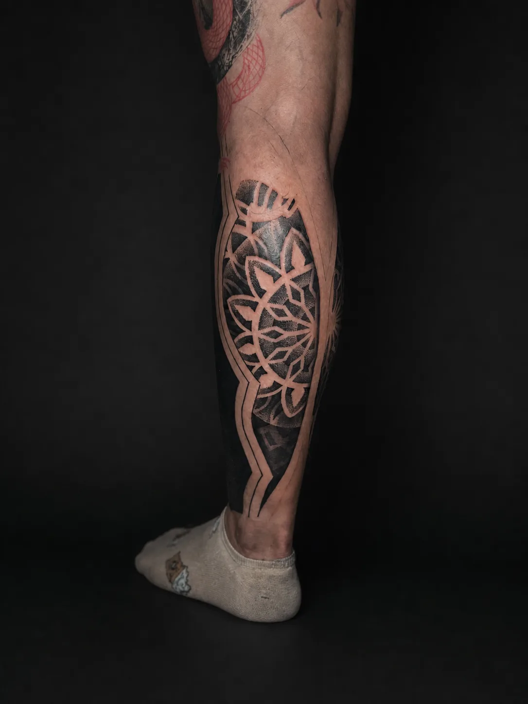 Geometrisches Blackwork mit präzisen Negativflächen am Unterschenkel